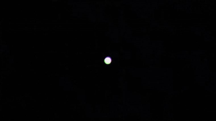 An almost entirely black frame with a single white dot at the centre.